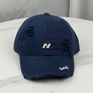 Close-up of distressed navy baseball cap with white N embroidery and ripped details