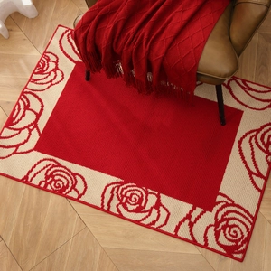 Festive red entry rug with rose patterns on wood floor with chair and blanket
