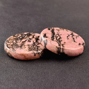 Macro shot of two polished pink rhodonite crystal discs with black dendritic textures