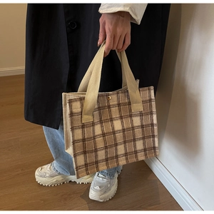 Detailed view of a brown plaid canvas tote bag with beige handles for daily commute