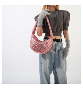 Detailed view of metallic pink quilted crescent shoulder bag styled with casual outfit