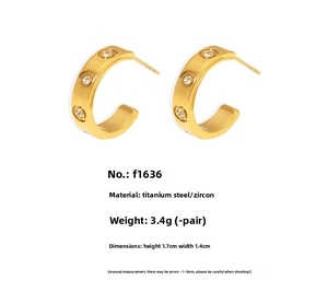 Macro detail of 18K gold plated C-shaped earrings with round zircon inlay and screw texture