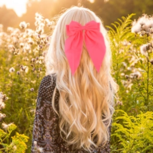 Fluorescent pink bow hair clip accessory shown on model from back view for women