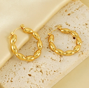 Detail of 18K gold plated hollow earrings on a premium silk and stone background