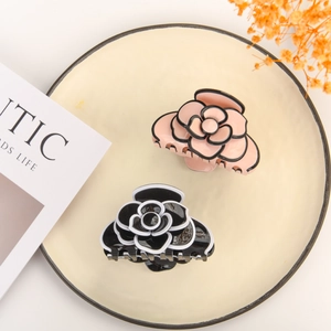 Close-up of camellia hair claw clips in pink and black with layered resin petal texture