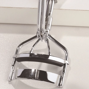 Macro shot of silver stainless steel eyelash curler with premium black silicone pressure pad