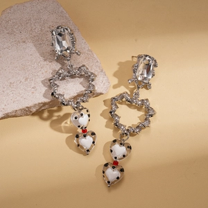Détail de boucles d'oreilles argentées torsadées avec cristal et pendentifs cœur à pois
