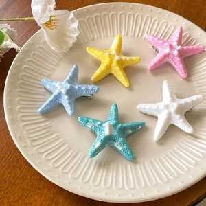 Five colorful starfish hair clips in candy colors on an elegant ceramic plate