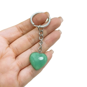 Natural heart shaped green stone keychain with silver metal ring held by hand