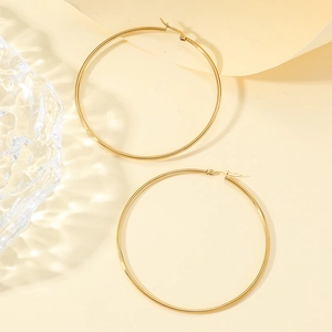 Minimalist large stainless steel gold hoop earrings for women on beige background