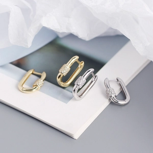 Close-up of U-shaped S925 silver and gold earrings with pavé sparkling zircon stones