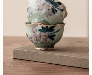 Gros plan de tasses à thé en céramique empilées avec glaçure craquelée et motif magnolia