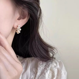 Close-up of pearl cluster C-shaped earrings with crystals on woman's ear