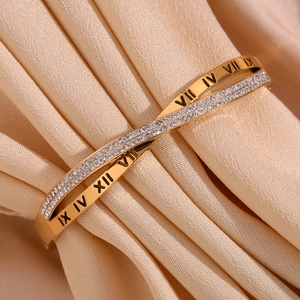 Detail of 18K gold-plated crisscross bracelet featuring Roman numerals and micro-pave crystals
