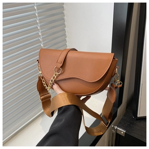 Detail shot of brown saddle bag with stylish wide strap and decorative metal chain