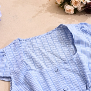Detailed close-up of blue plaid square neck blouse featuring fabric-covered buttons