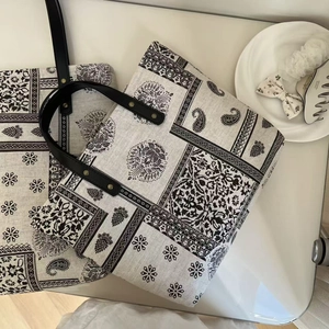 Detail of vintage paisley pattern on beige canvas tote bags with black leather handles