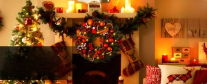 Detail of Christmas wreath with LED lights and festive ornaments on a cozy warm fireplace