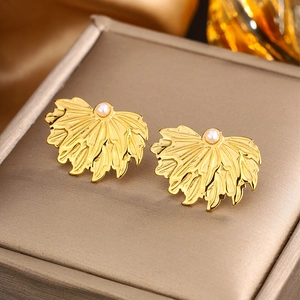 Macro view of gold leaf stud earrings with wavy texture and white pearl detail