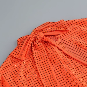Gros plan sur le tissu orange texturé orné de strass et d'un nœud papillon élégant