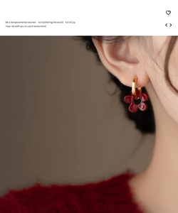 Vue détaillée d'une boucle d'oreille fleur rouge foncé vintage portée par un mannequin