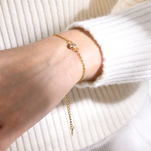 Close-up of a minimalist gold bracelet featuring a bezel-set round zircon on a wrist