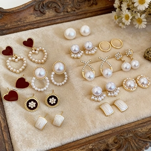 Close-up of French vintage gold earrings with pearls and crystals on a rustic wood background