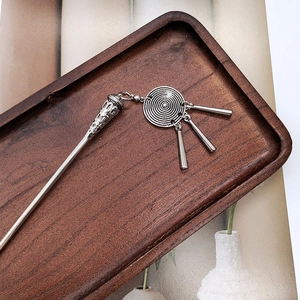 Detail of silver ethnic hair pin with tassel pendants on a vintage wooden tray