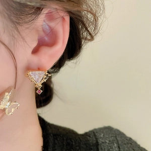 Gros plan détaillé d'une boucle d'oreille vintage dorée avec zircons rouges et clairs