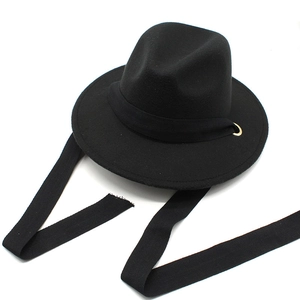 Detail of black wool fedora featuring gold eyelets and textured herringbone ribbon tie