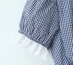 Detailed view of blue plaid cuff featuring white openwork embroidery lace and puff sleeve