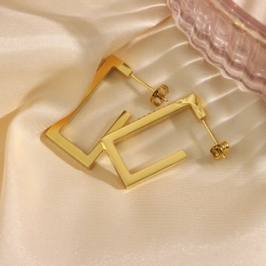 Detail of 18K gold-plated rectangular earrings with crystals on champagne satin background