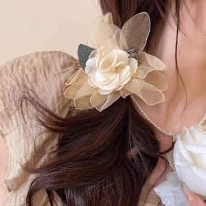 Detailed close-up of champagne organza rose hair claw clip with green leaf accents