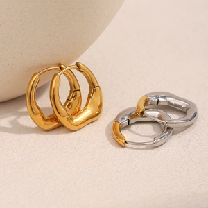 Detailed close-up of irregular 18K gold plated and bicolor stainless steel hoop earrings