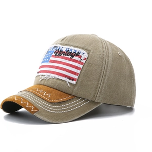 Vintage washed khaki baseball cap with US flag patch and frayed lettering on white background