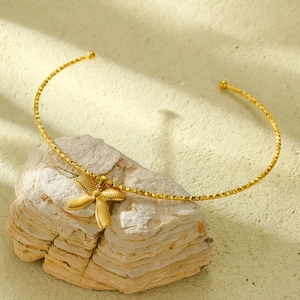 Detail of a gold stainless steel bow pendant necklace displayed on a natural stone