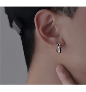 Close-up of retro silver hoop earring with fleur-de-lis pattern and CHVALRY engraving