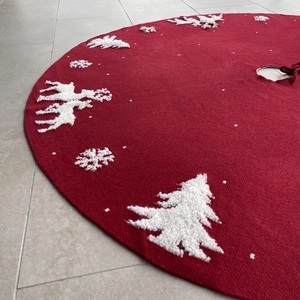 Detail of red knitted Christmas tree skirt with white reindeer and snowflake patterns