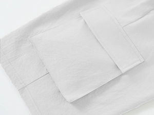 Detailed close-up of light grey cargo shorts featuring a large flap pocket and precision stitching