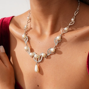 Detail of silver rhinestone necklace with teardrop pearl on a red velvet dress