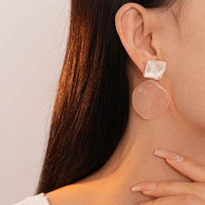 Close-up of pink resin geometric earrings with shimmering texture on a model