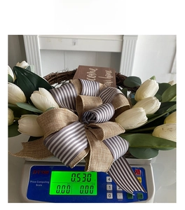 Detailed weight display of tulip wreath on scale featuring white flowers and bow
