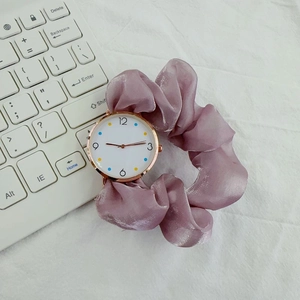 Close-up of elegant purple silk ribbon scrunchie strap and rose gold round watch dial