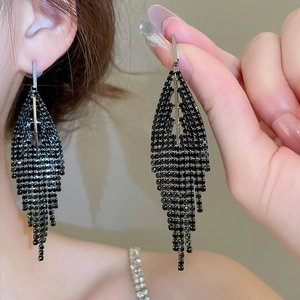 Detail of long black fringe earrings with triangular rhinestone tassels and silver studs