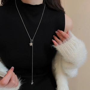 Silver star pendant Y-necklace styled on a black turtleneck with a white cardigan