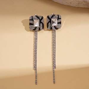 Macro detail of geometric square silver pin earrings with crystal tassel fringe