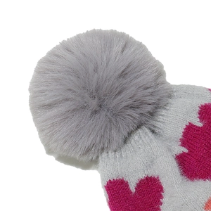 Detailed close-up of knitted winter hat with pink heart patterns and fluffy pom-pom