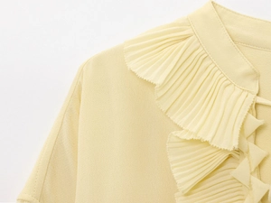 Detailed view of the pleated ruffles and textured fabric on a yellow chiffon top