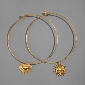 Close-up of 18K gold plated heart and sun face pendants on rigid wire necklaces