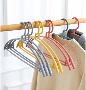 Detail showing non-slip wide shoulder coat hangers with beige sweater on wooden rail